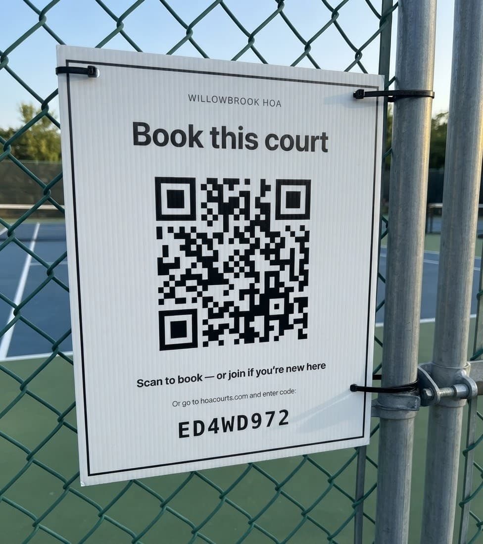 A printed HOA Courts QR sign zip-tied to a court fence